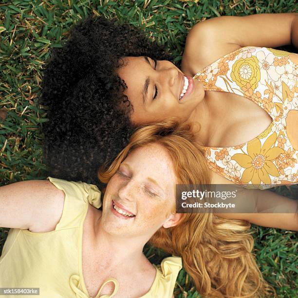 elevated view of two teenage girls (17-18) lying on the grass, laughing - only teenage girls stock pictures, royalty-free photos & images