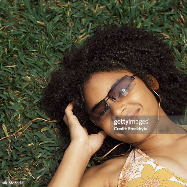 elevated view of a teenage girl (17-18) lying on the grass with sunshades - square neckline fotografías e imágenes de stock