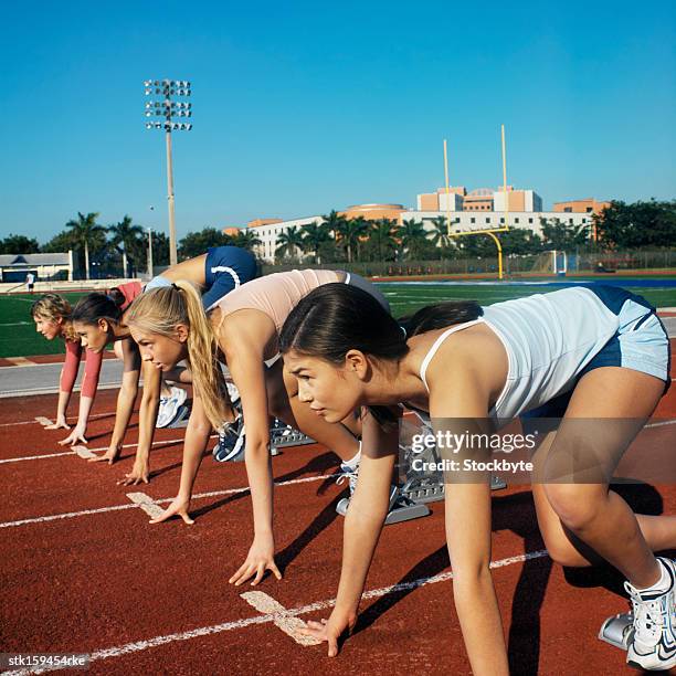 teenage girls at starting positions in a field race - sprinter positions stock-fotos und bilder
