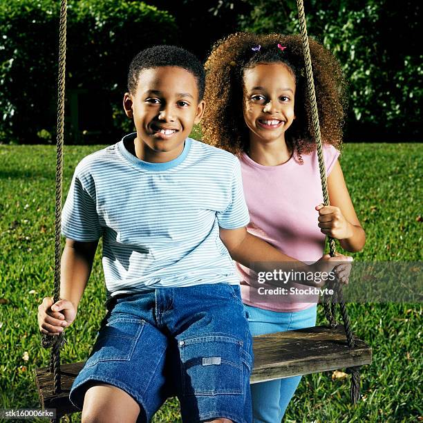 portrait of a brother and sister on a swing - middle childhood stock pictures, royalty-free photos & images