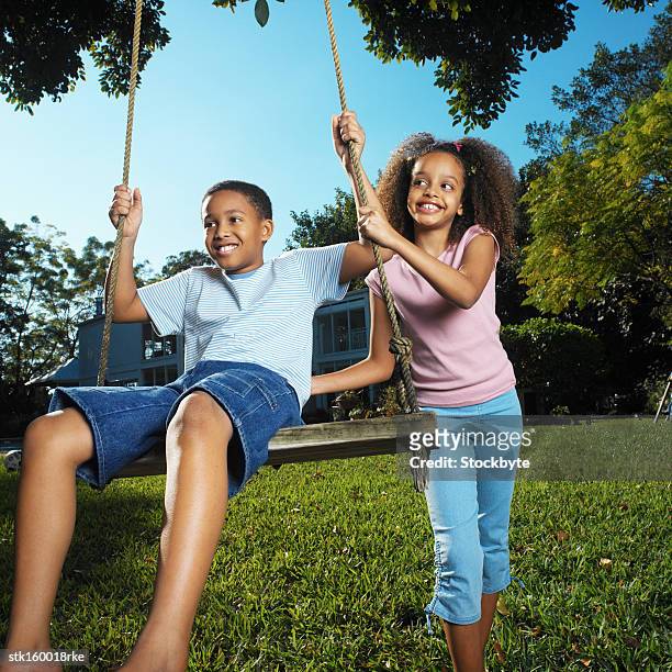 brother (12-13) and sister (8-9) playing with swing - 13 year old girls in shorts stock pictures, royalty-free photos & images