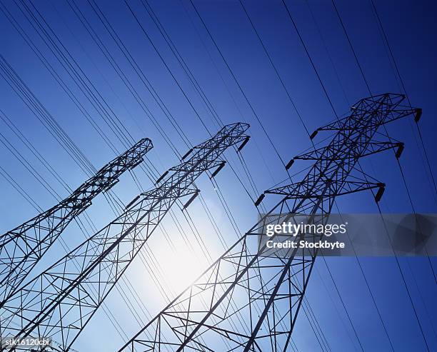 low angle view of high tension cable towers - high and low stockfoto's en -beelden