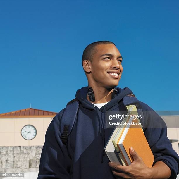 young man holding books looking sideways - university of california students protest 32 percent fee hike stockfoto's en -beelden