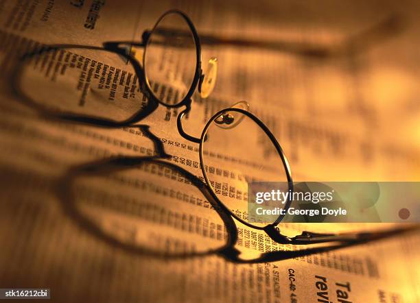 close-up of spectacles lying on a newspaper - share prices of consumer companies pushes dow jones industrials average sharply higher stockfoto's en -beelden