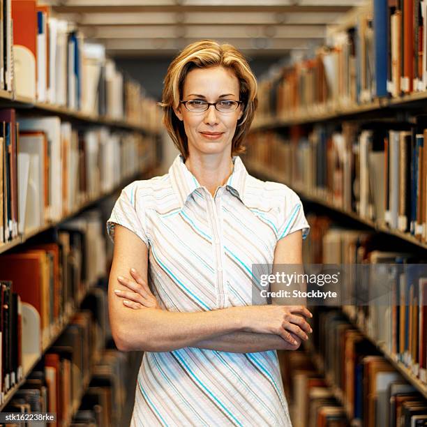 portrait of a young woman standing between two shelves of files - between stock-fotos und bilder