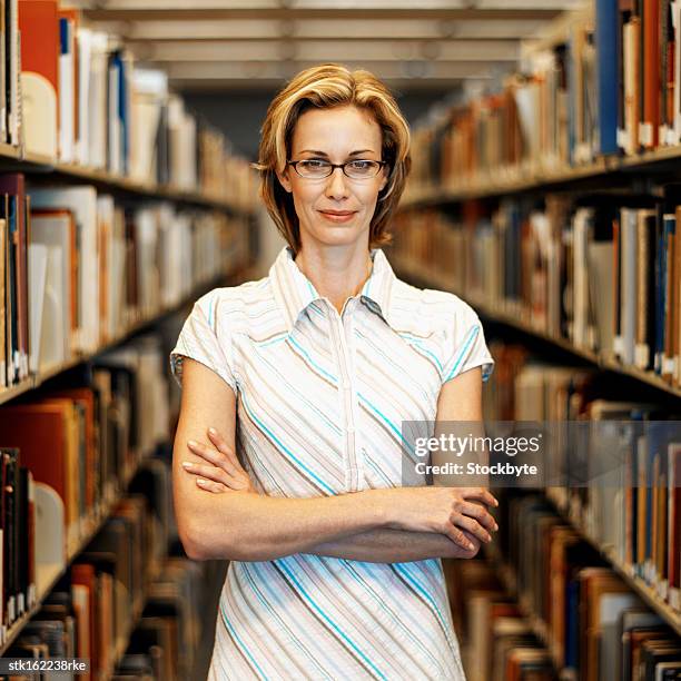 portrait of a young woman standing between two shelves of files - between bildbanksfoton och bilder