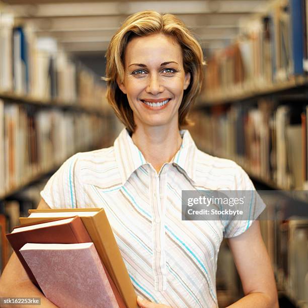 portrait of a young woman standing between two shelves of files smiling - between stock-fotos und bilder