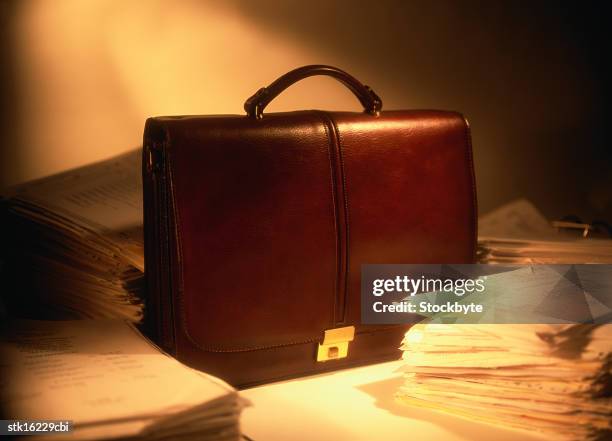 a briefcase lying between stacks of paper - between stock-fotos und bilder