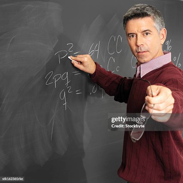 side view of a male teacher writing on blackboard holding his glasses - jerry lewis hosts special screening of the nutty professor stockfoto's en -beelden