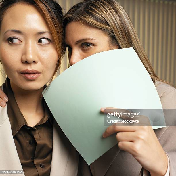 two businesswoman whispering in ear close-up - ear close up women stock-fotos und bilder