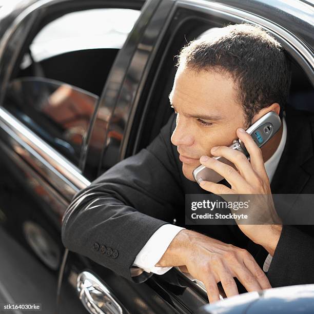 businessman hanging out of car door on mobile phone - door stockfoto's en -beelden