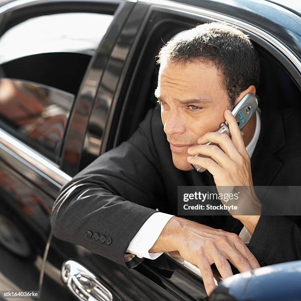 businessman hanging out of car door on mobile phone - door stockfoto's en -beelden