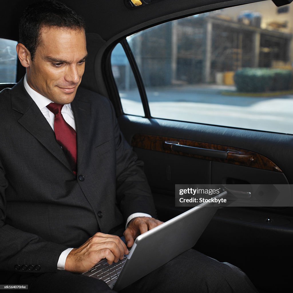 Businessman working on laptop while sitting in a car