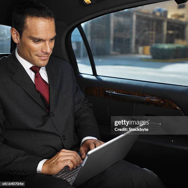 businessman working on laptop while sitting in a car - young-urban-professional-person stock-fotos und bilder