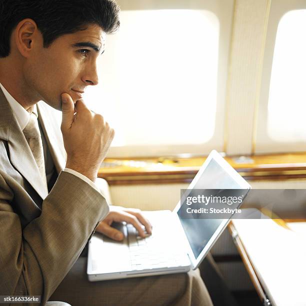 side profile of businessman using laptop in an airplane - young-urban-professional-person stock-fotos und bilder
