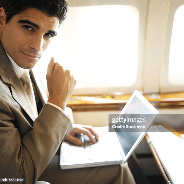 portrait of a businessman using laptop in an airplane - young-urban-professional-person stock-fotos und bilder