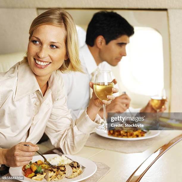 business executives eating and drinking in an airplane - young-urban-professional-person stock-fotos und bilder