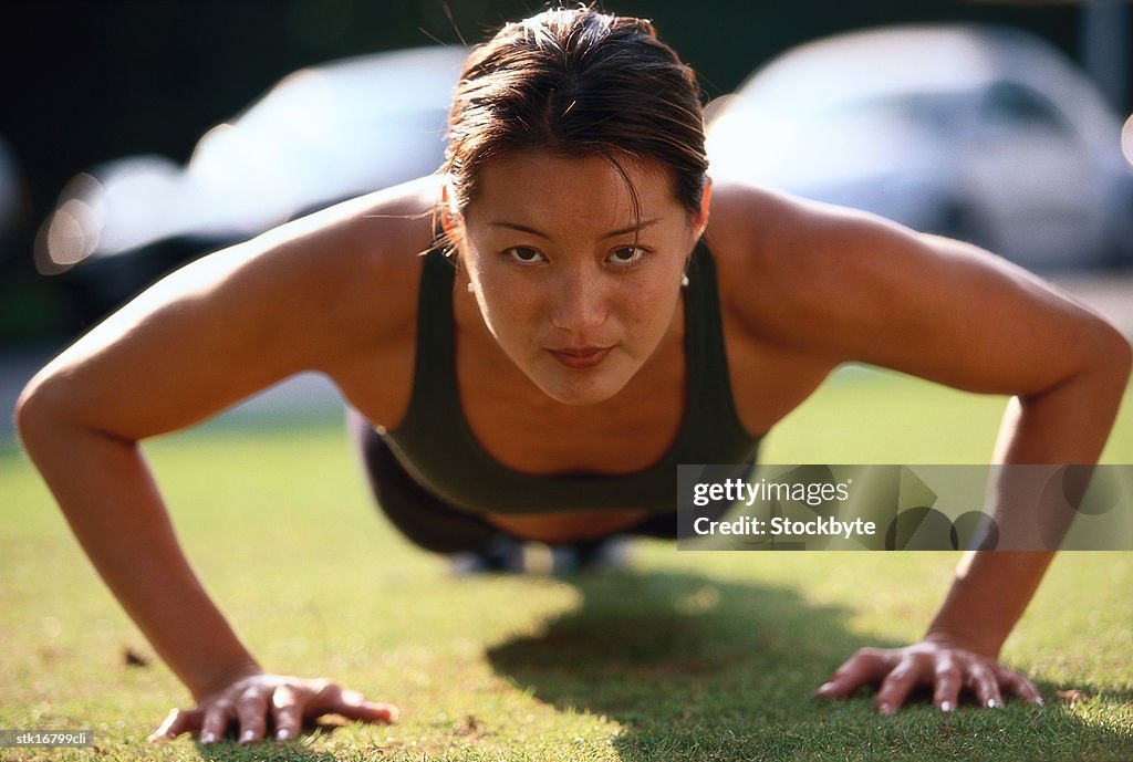 Portrait of a young woman doing push ups