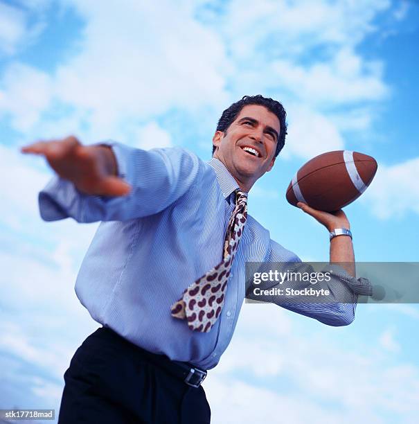 low angle view of a businessman about to throw a football - about stock pictures, royalty-free photos & images