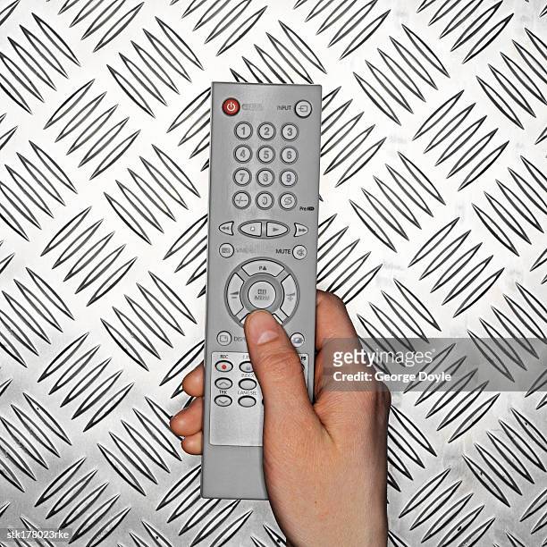 a hand holding a remote control - control photos et images de collection