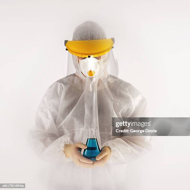 person in full protective gear holding a beaker with fluid - unveiling of life size statue of andrea bocelli at keep memory alive event center stockfoto's en -beelden