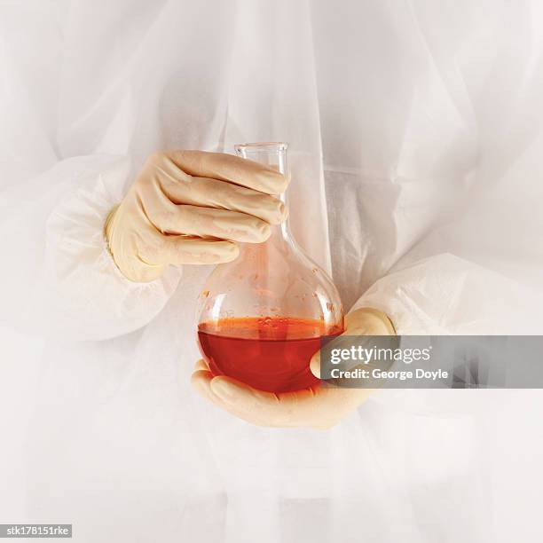 scientist wearing a fully protective suit holding a flask with red liquid - unveiling of life size statue of andrea bocelli at keep memory alive event center stockfoto's en -beelden