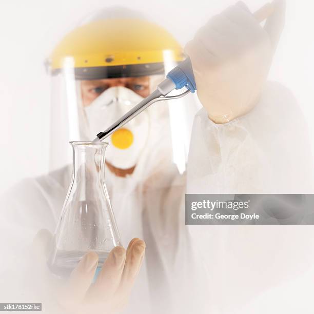 scientist wearing a fully protective suit adding liquid into conical flask - unveiling of life size statue of andrea bocelli at keep memory alive event center stockfoto's en -beelden