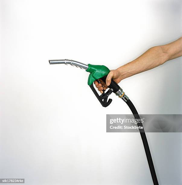 outstretched hand holding gasoline dispenser - dispenser stockfoto's en -beelden