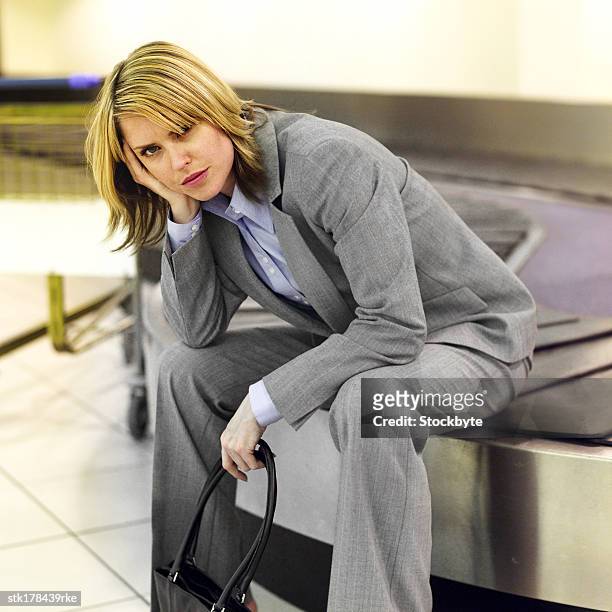 portrait of a young woman sitting on the conveyor belt and waiting - belt stockfoto's en -beelden