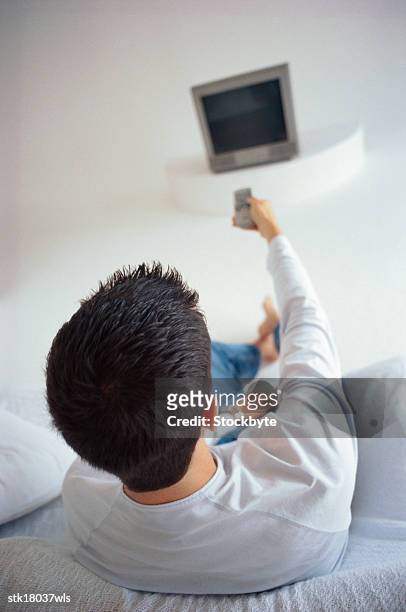 elevated view of a man pointing a remote control at a tv - control photos et images de collection