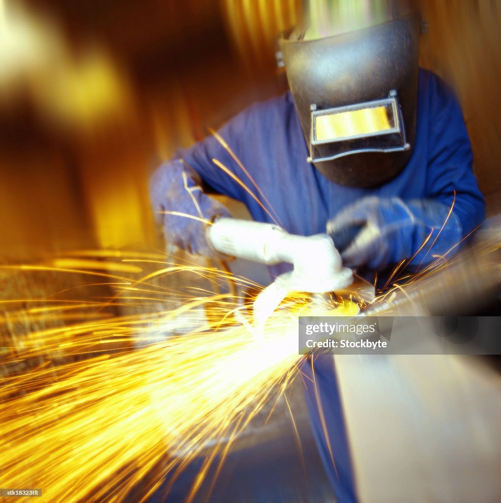 Person in overalls using a metal grinder