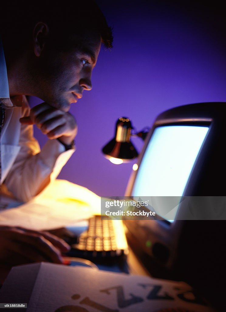 Side profile close-up of a man staring at a lit computer screen