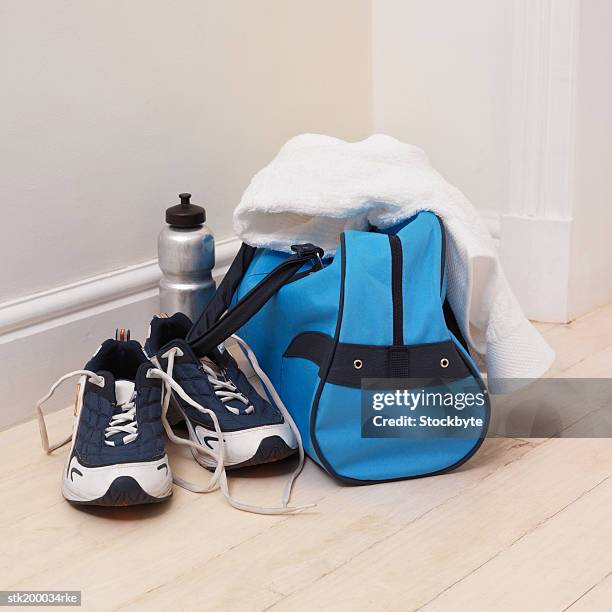 elevated view of sports bag and water bottle and running shoes and a towel - sporttasche stock-fotos und bilder