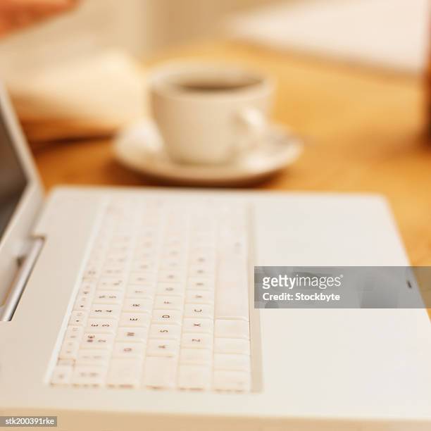 close up elevated view of a laptop with a cup of coffee next to it - next stockfoto's en -beelden