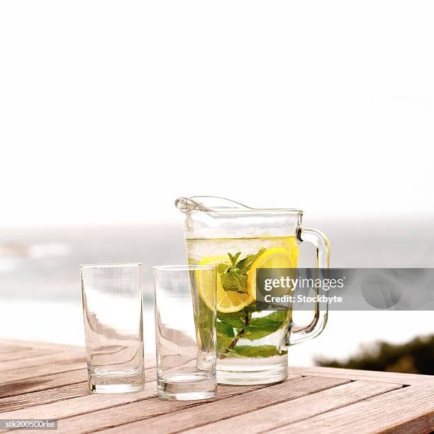 close up of a jug of drink with mint and lemon and 2 glasses - lemon mint stock pictures, royalty-free photos & images