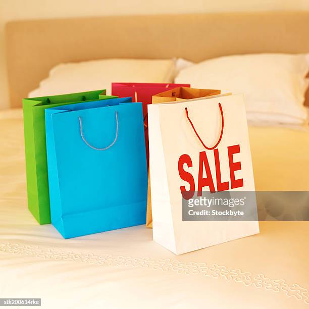 shopping bags on a bed and one bag with sale written on it - sale stockfoto's en -beelden