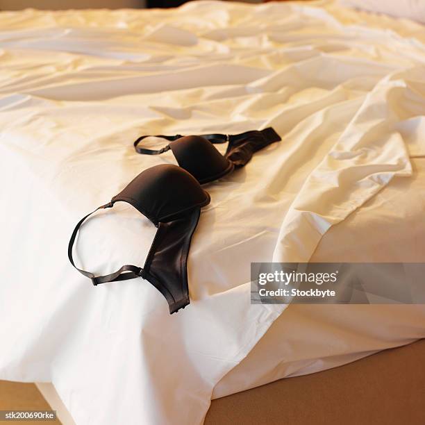 unmade bed with a bra on top of it - büstenhalter stock-fotos und bilder