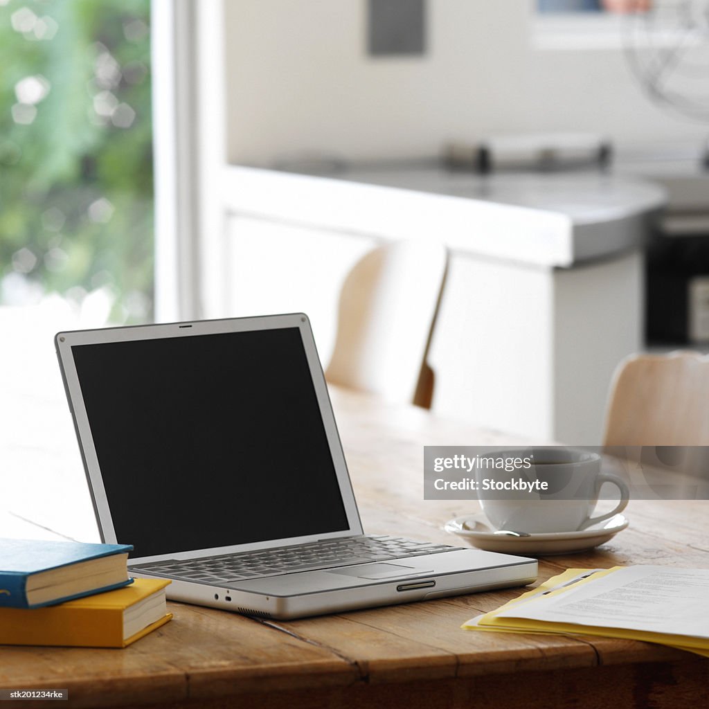 Close up of a laptop on a kitchen table with a cup of coffee