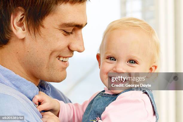 close up view of father holding baby  daughter (12-18 months) and smiling - genderblend stock pictures, royalty-free photos & images