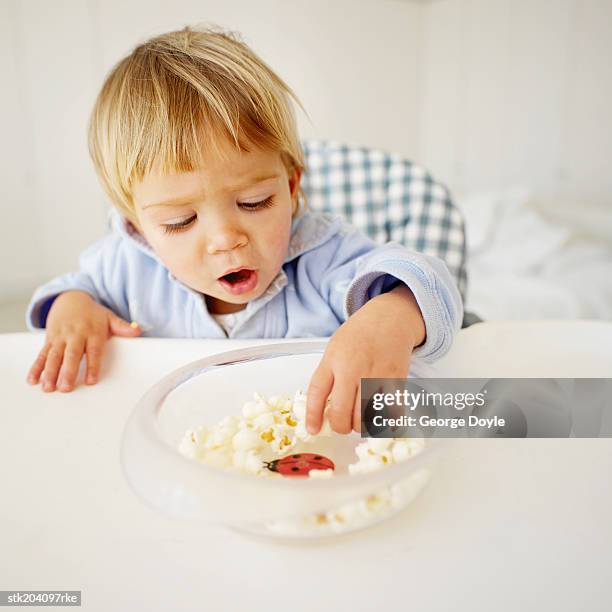 elevated view of baby boy (18-24 months) eating popcorn - only baby boys stock pictures, royalty-free photos & images