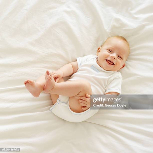 elevated view of a baby (12-18 months) lying on a bed - only baby boys stock pictures, royalty-free photos & images