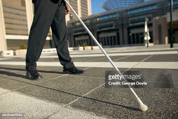 low angle low section view of a blind man walking with the aid of a white stick - stick plant part stockfoto's en -beelden