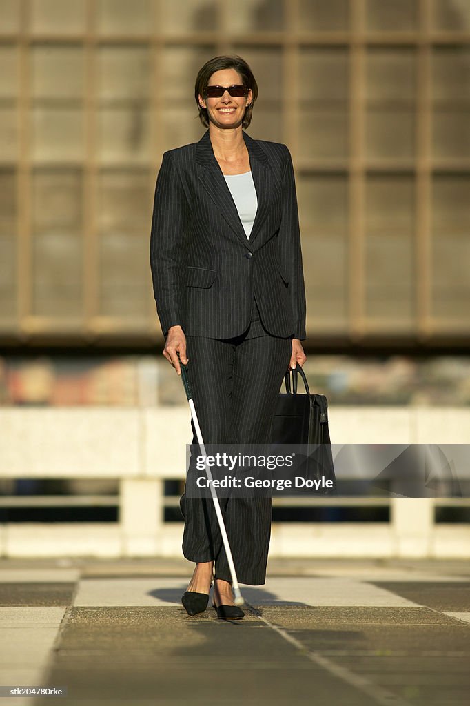 Blind businesswoman walking with the aid of a white stick