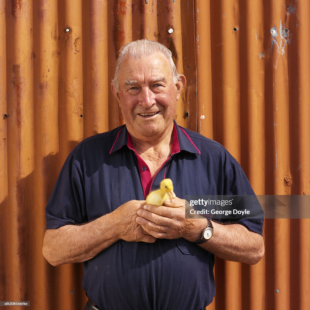 Portrait of a man holding a duckling