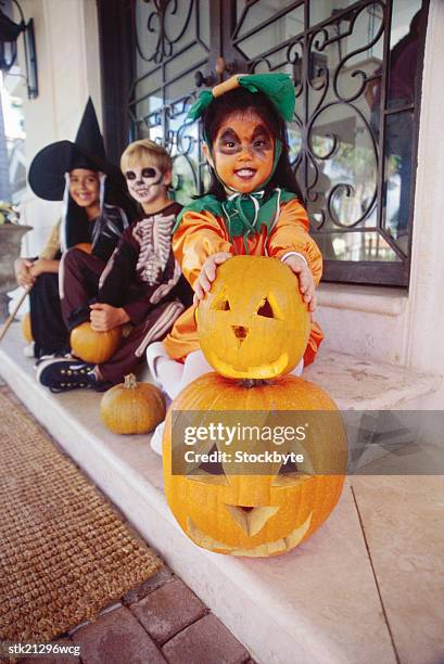 portrait of a children in halloween costumes sitting behind carved pumpkins - boys wearing tights stock-fotos und bilder