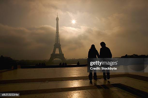 nighttime view of eiffel tower and couple standing admiring it - travel14 stock pictures, royalty-free photos & images