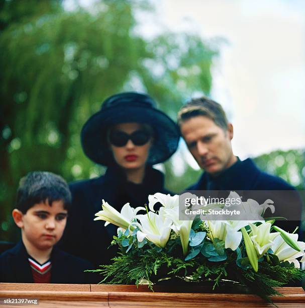 portrait of a young couple and their son standing over a coffin - lily family stock pictures, royalty-free photos & images