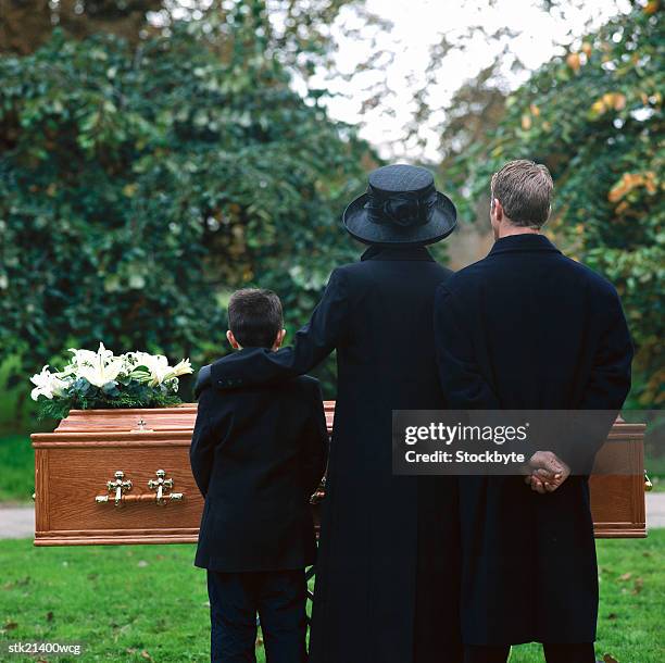 portrait of a young couple and their son standing in a cemetery - bare kids foto e immagini stock