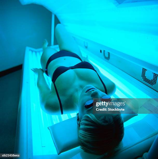 high angle view of a woman lying in a tanning machine - tanning bed stock pictures, royalty-free photos & images