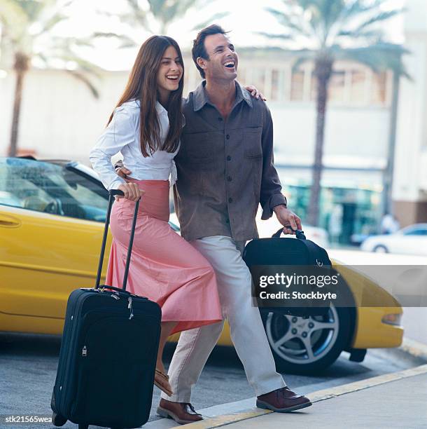 view of a young couple walking with luggage - open roads world premiere of mothers day arrivals stockfoto's en -beelden